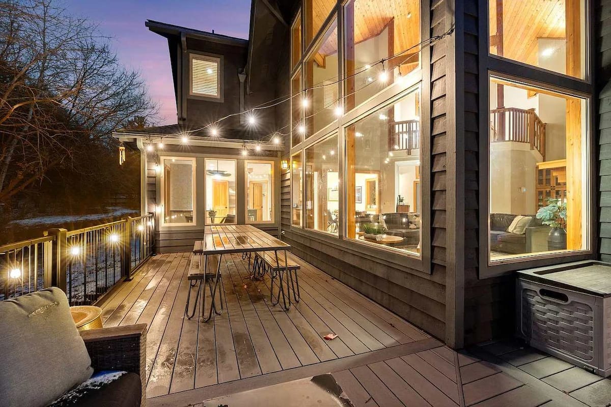 Wraparound deck with string lights at twilight, overlooking the pine forest